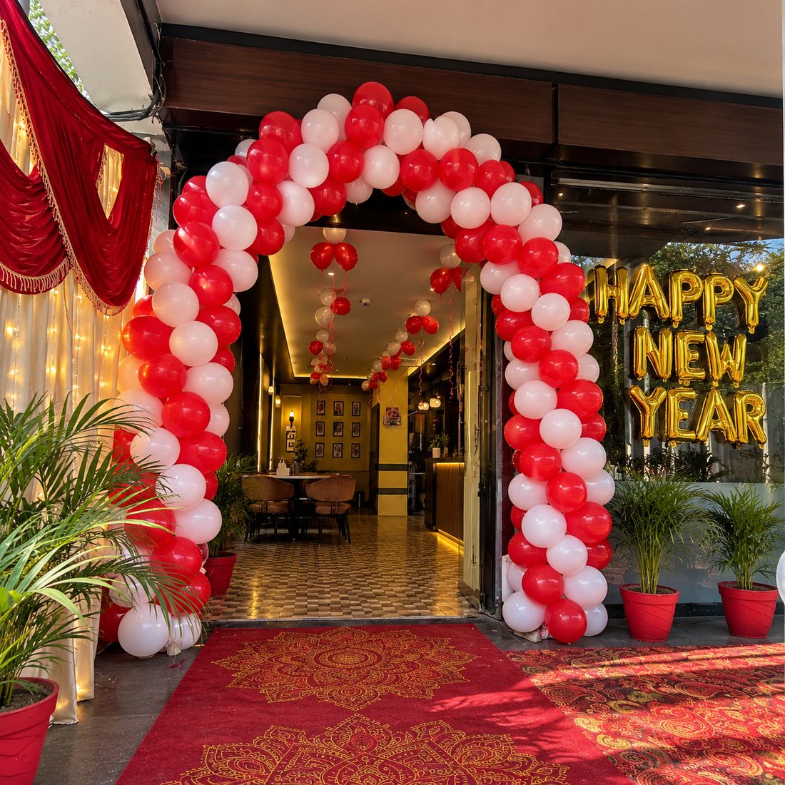 New Year decor: red and white balloon arch at a restaurant entrance with gold Happy New Year letters