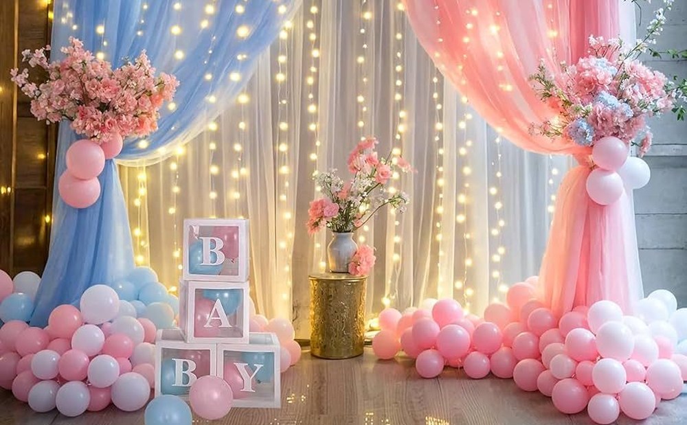 Baby shower decor with blue and pink drapes, fairy lights, BABY letter blocks, flowers and balloons