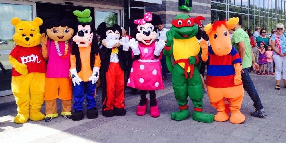 Costumed mascot characters posing outside a building at a kids party entertainment booking